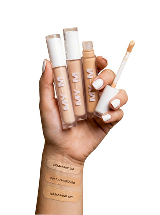 Hand holding 3 types of MYM concealer tubes with swatches